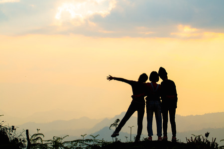 Silhouette of happy friends  in sunset sky evening time background,  Group of young people having fun on summer vacation,  Youth lifestyle, party and friendship concept, Copy space.の写真素材