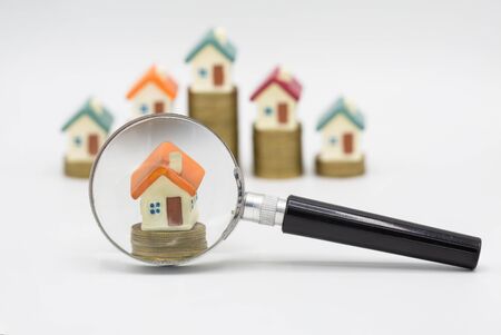 House searching concept with a magnifying glass on white background. Stack coin and bar graph with...