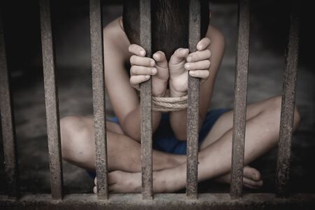 The child was tied up with a rope and was in a cell. Stop violence against children, child labor, human rights, human traffickingの写真素材