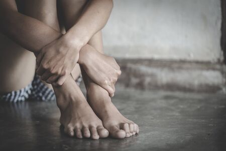 Scared young woman sitting in the corner of her bedroom, despair rape victim waiting for help,The concept of stopping violence against women and rape.の写真素材
