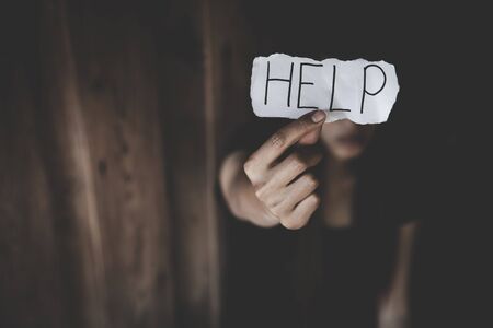 Women sitting alone with depressed expression and showing a paper with a help text. Stop violence against women.の写真素材