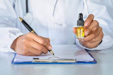  Doctor holding a bottle of hemp oil and offer to patient medical marijuana and oil.  alternative...