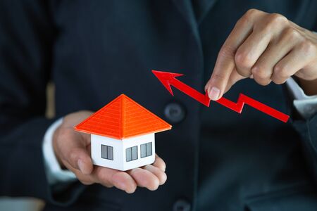 Businessman Holding  Graph Over The Increasing House Miniature, Real estate investment,investment mortgage finance and home loan business, growth and money.の写真素材