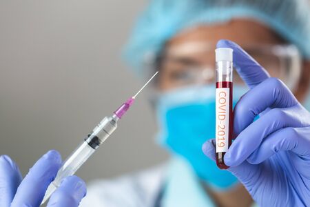 Doctor  hand in blue nitrile gloves holding flu, measles, coronavirus vaccine. covid-19 virus,...
