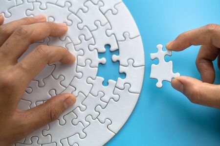 Hand placed the last piece of the jigsaw puzzle, Pieces of jigsaw puzzle in man's hands.の写真素材