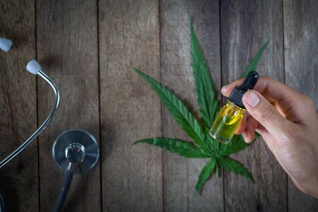 Hand holding bottle of Cannabis oil in pipette, natural herb, esearching hemp oil extracts for medical purposes, alternative remedy or medication, CBD substances in hemp oil.の写真素材