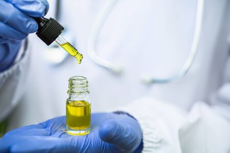 The hands of scientists dropping marijuana oil for experimentation and research, ecological hemp plant herbal pharmaceutical cbd hemp oil from a jar.の写真素材