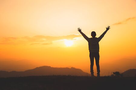 Man rise hand up on top of mountain and sunset,  Freedom and travel adventure concept. Religious beliefs, Copy space.の写真素材