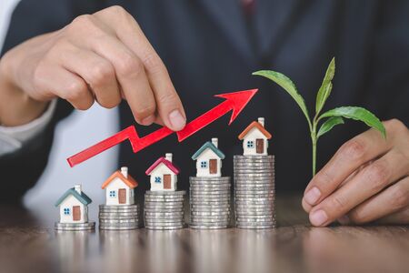 Businessman Holding  Graph Over The Increasing House Miniature, Real estate investment,investment...