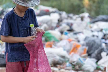 A poor boy collecting garbage waste from a landfill site in the outskirts, the lives and lifestyles...