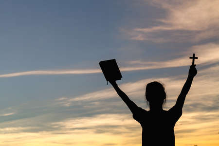 Women standing holding holy  bible for worshipping God at sunset background, Pray to the god,...