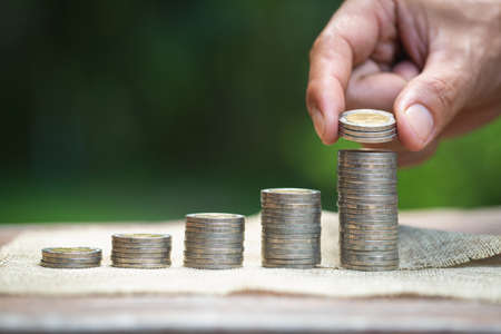 women hand put money coins to stack of coins. Business Growth concept.