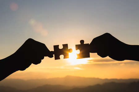Silhouette Woman hands connecting couple jigsaw puzzle piece against sunrise, Business solutions, target, success, goals and strategy conceptsの写真素材