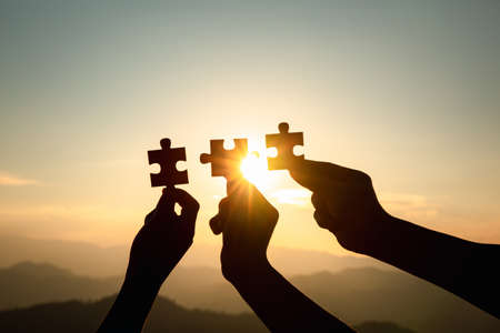 Silhouette of hand holding Jigsaw with Sunrise background. . symbol of association and connection. business strategy.の写真素材