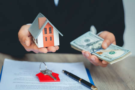 Real estate agent showing new house and bank note from Saving account for home insurance. House...