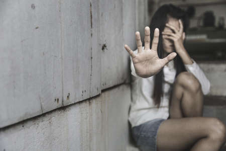 Stop hurting woman, woman stretching out hand While sitting against dark wall, Stop violence against women.の写真素材