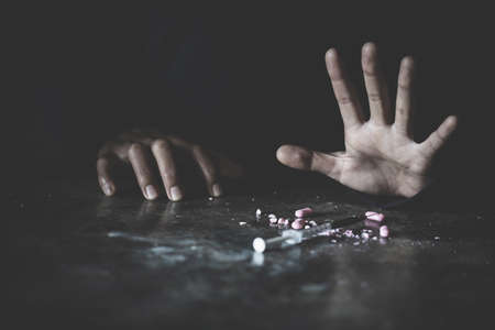 human hand trying to reach,  on  concrete floor. Drugs addiction and withdrawal symptoms concept. drugsInternational Day against Drug Abuse.の写真素材