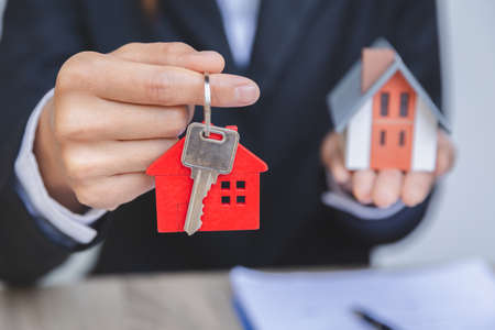 Businessman's hand holds house keys, house and real estate trading ideas.の写真素材