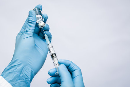 Female doctor holds syringe and bottle with vaccine for coronavirus curesの写真素材