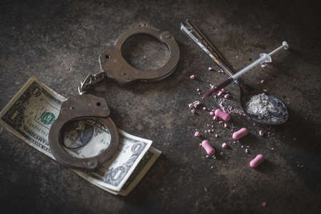 Drug syringe and cooked heroin on spoon and handcuffs . Concept - punishment for possession of...