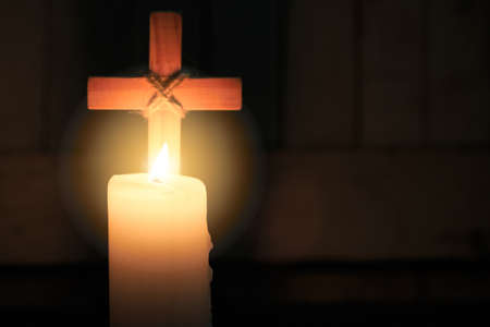The candle glows in front of the cross. Christmas, Easter and religious background with copy space.の写真素材