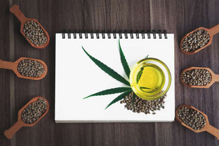 Hemp oil and hemp leaf on a blank notebook, space for text.の写真素材