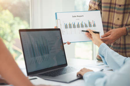 Young businessteam work on statistics and business graphs, discussing the charts and graphs showing...