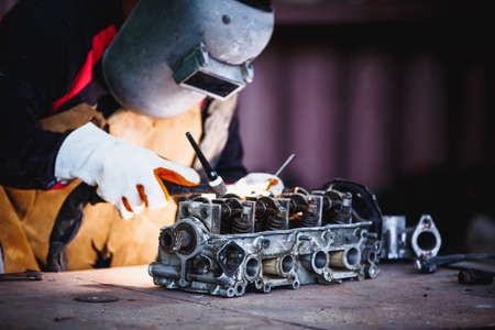The man in the face mask is welded by argon welding. Welder industrial worker welding with argon machine.の写真素材