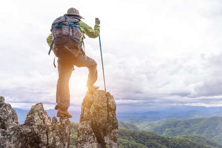 Active climbers enjoy the view.female backpacker with backpack and crutches enjoy the sunshine on the mountain, copy space.の写真素材