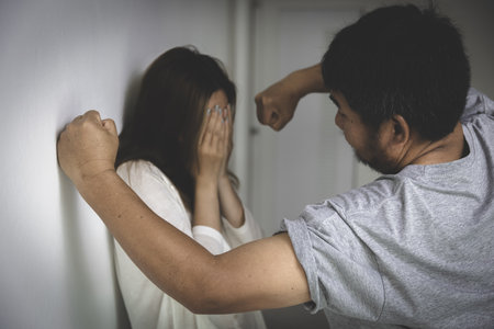 A man is about to attack a woman with a fist.Woman conceals her face in fear of domestic violence.の写真素材