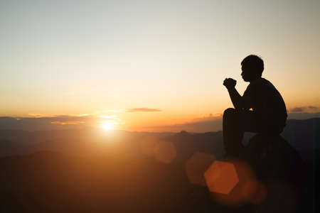 Man praying at sunset mountains raised hands Travel Lifestyle spiritual relaxation emotional concept, Freedom and travel adventure.の写真素材