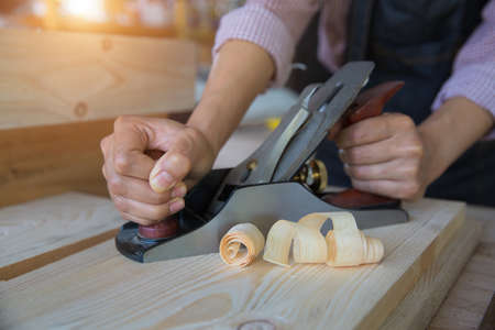 A carpenter works with equipment on a wooden table in a carpentry shop.の写真素材