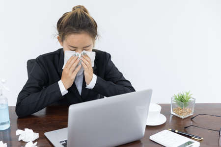 Female employee wearing a medical mask while working alone, Sickness while working.の写真素材