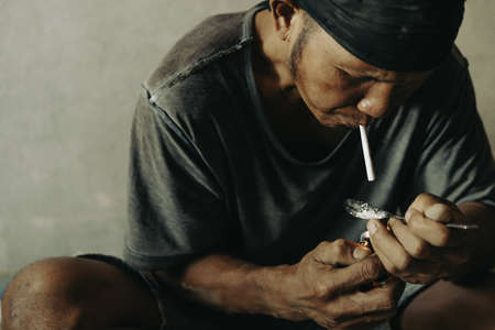Drug addicts in the dark room. Addict/junkie preparing drugs with a spoon and lighter. White powder and a syringe. Drug concept. International drug abuse day.の写真素材