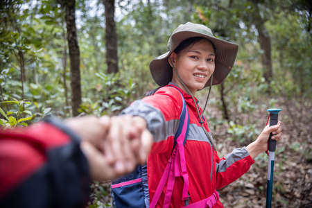 young couple on a hiking trip.  young man and woman hikers holding hands while walking on mountain trail.の写真素材