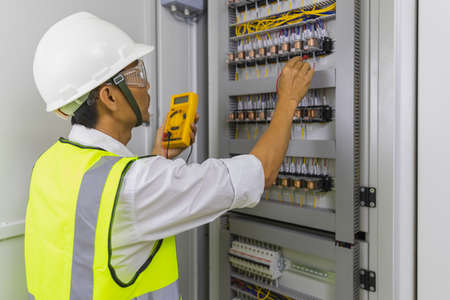 Electrician installing electric cable wires and fuse switch box. Multimeter in hands of electricians...