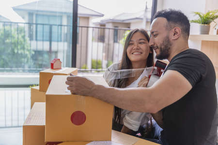 The concept of moving house. Closeup of Couple packing cardboard boxes to move to a new home.