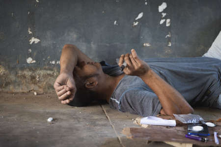 Human hand of a drug addict and a syringe with narcotic syringe lying on the floor. Anti drug...