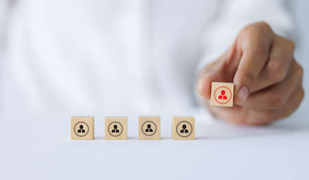 Hand holding a wooden block with people icon above mint square. Building a strong team, HR concept...