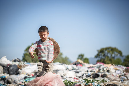 children work at these sites to earn their livelihood. Poverty concept. A poor boy collecting garbage waste from a landfill site in the outskirts .の写真素材