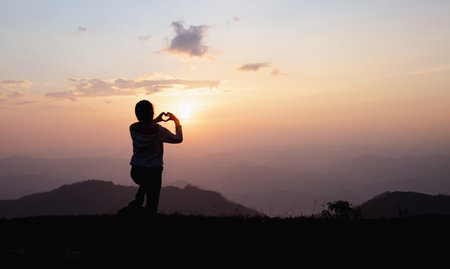 Hands in shape of love heart, Female hands in the form of heart against the sky pass sun beams. Happy  in love.の写真素材