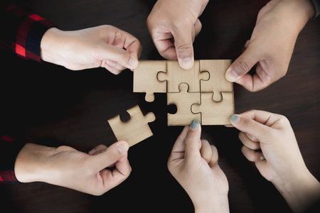 Hands of diverse people assembling jigsaw puzzle, team put pieces together searching for right match, help support in teamwork to find common solution concept, top close up viewの写真素材