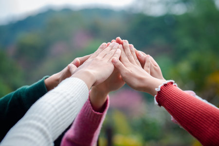 A diverse group of people connects their hands as a supportive sign expressing a sense of teamwork....