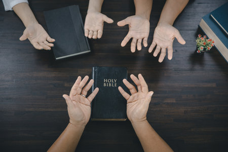 A group of Asian Christians sits inside a Catholic Church praying for God's blessing, the pale sun...