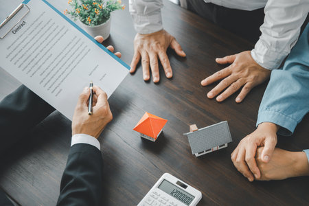 Home sales and home insurance concept. Real estate agent talked about the terms of the home purchase agreement and asked the customer to sign the documents to make the contract legally.の写真素材