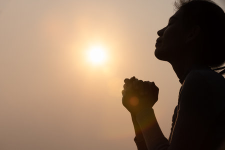Silhouette of  Woman raising his hands in worship, woman praying for god, Christian Religion concept background.の写真素材