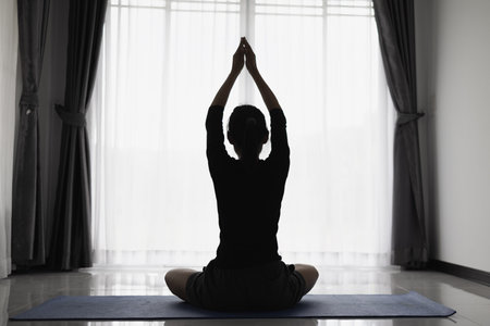 Asian woman practicing yoga indoors on a yoga mat Practice meditation to relax. Home exercise ideas.の写真素材