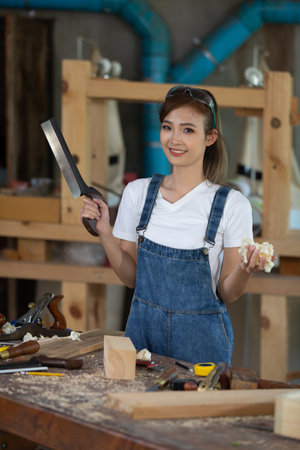 Young woman is training to be a carpenter in workshop. Carpenter working with equipment on wooden table. woman works in a carpentry shop.の写真素材