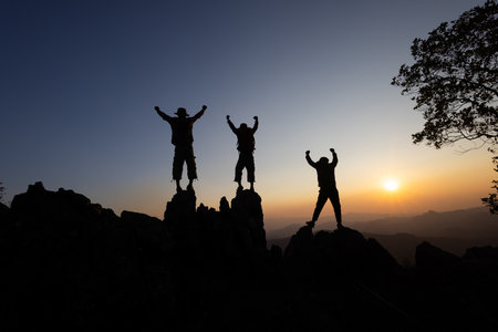 Silhouette of a team of climbers ascending a rugged mountain, showcasing unity and determination, Embracing a culture of teamwork for continuous growth and success.の写真素材