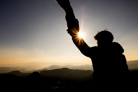 Silhouette of People helping on peak mountain and sunrise background climbing team work success business concept. People on peak mountain climbing helping team work.の写真素材